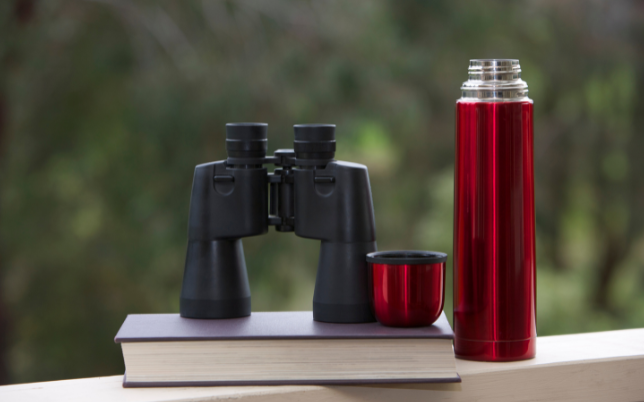 pair of binoculars and a flask sat on a table top